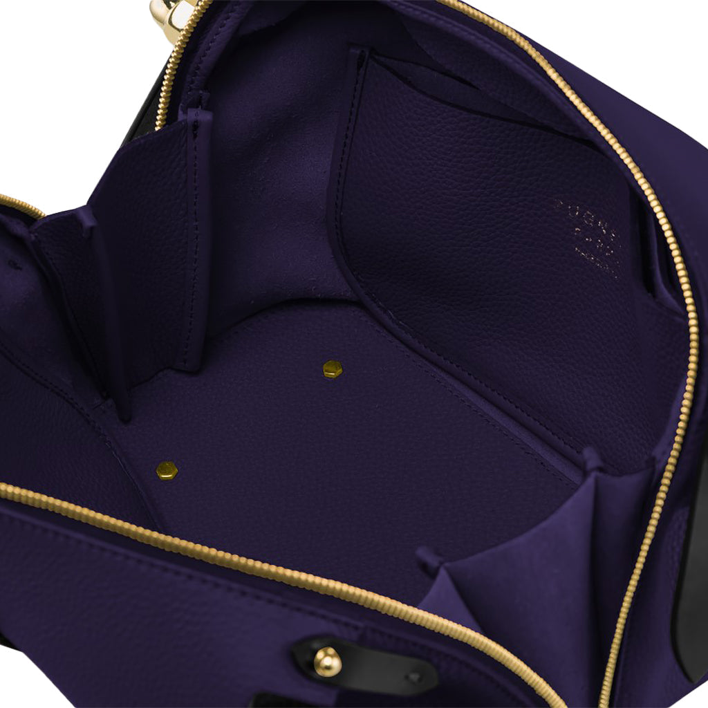 Interior view of a purple leather handbag with compartments and gold hardware