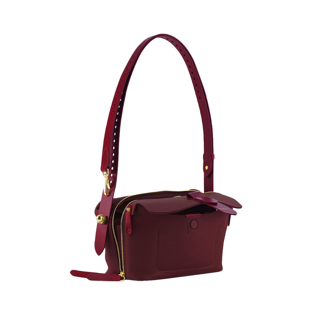 Minimalist burgundy leather shoulder bag with gold accents and adjustable strap