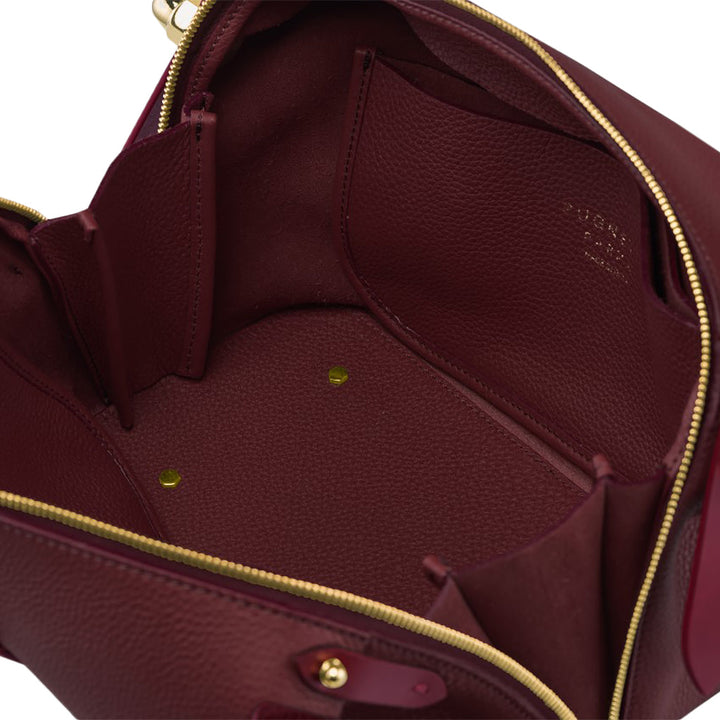 Open maroon leather handbag with multiple pockets and gold zipper detailing