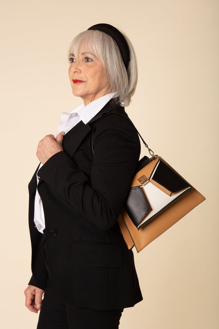 Stylish older woman wearing a black blazer, holding a fashionable handbag