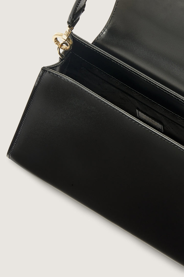 Black leather handbag with gold clasp and open flap showing inner compartment