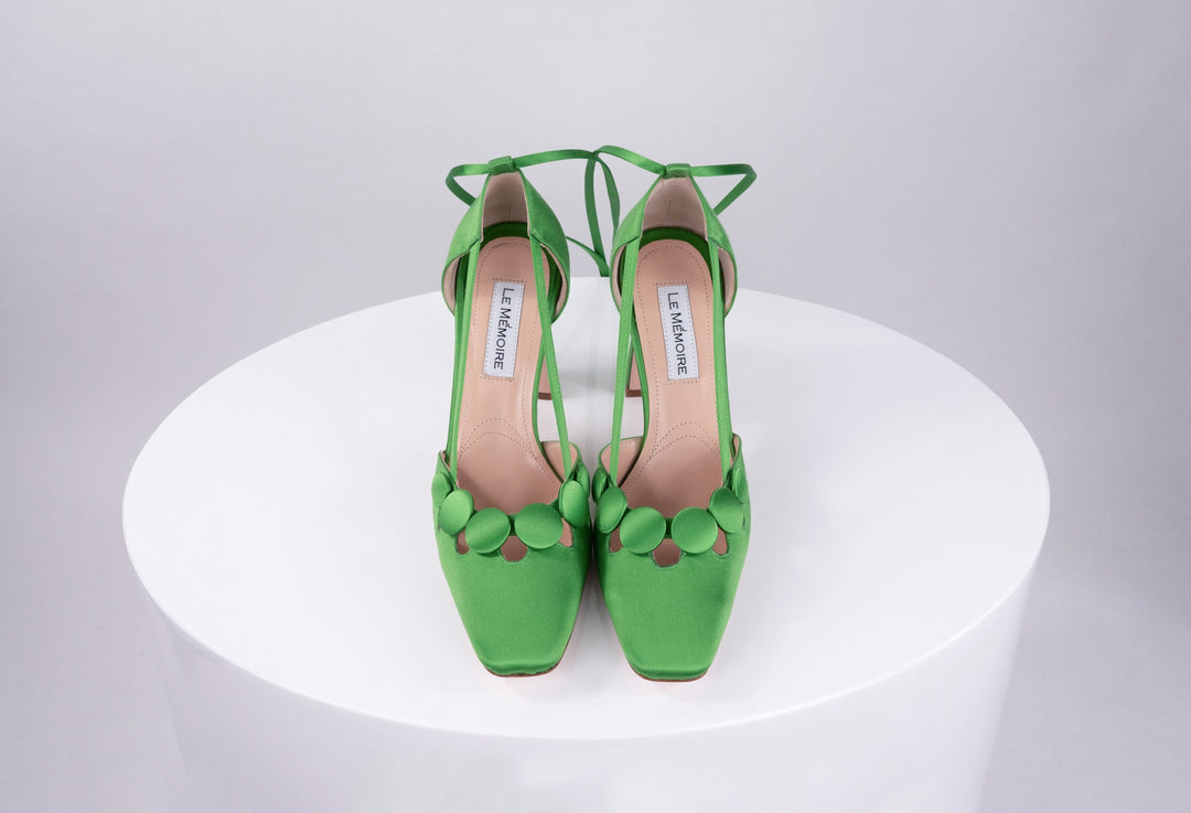 Green high-heeled shoes with ankle straps on a white background