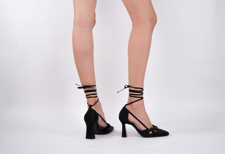 Woman wearing black lace-up high heels against white background