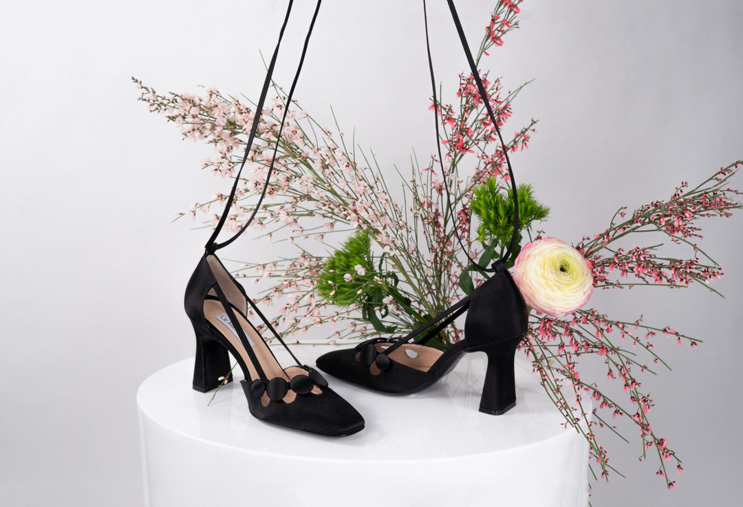 Elegant black high-heeled shoes with floral background display