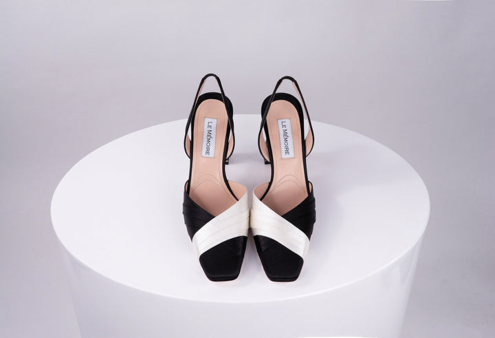 Black and white strappy platform heels displayed on a round white surface