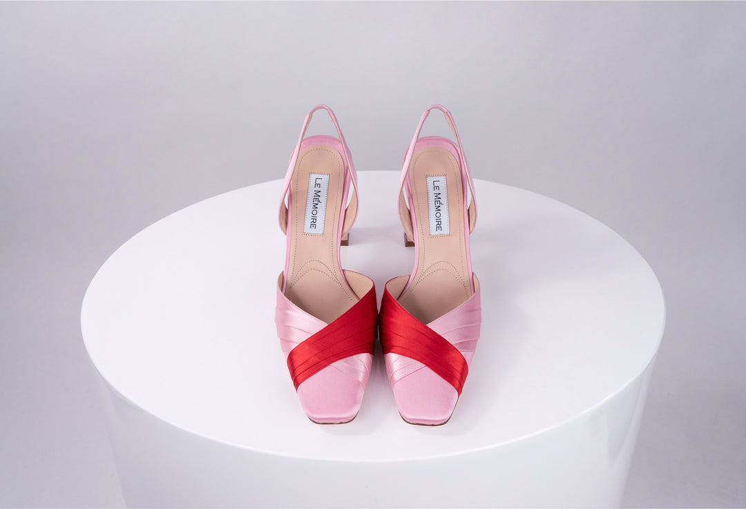 Pink and red high-heeled shoes with criss-cross design on white background