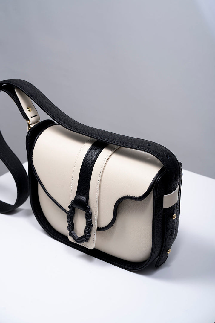 Black and white leather shoulder bag with buckle detail on a white surface