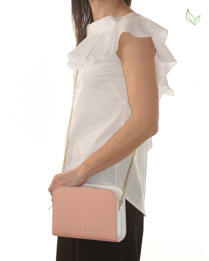 Woman holding a stylish pink and white shoulder bag with gold chain