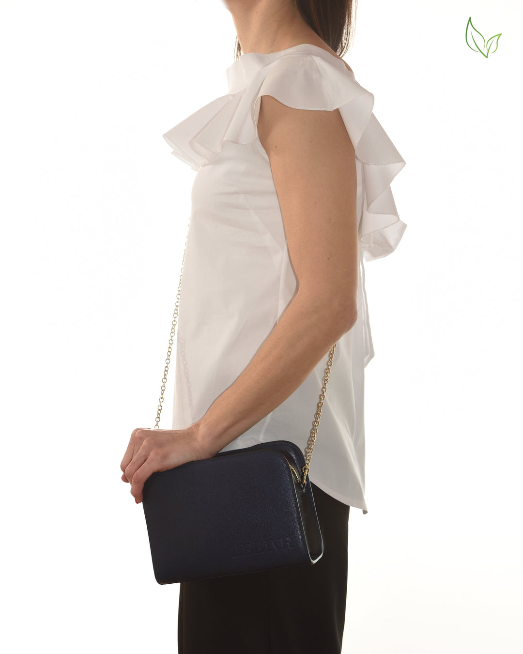 Woman wearing white ruffled blouse with blue clutch purse and chain strap