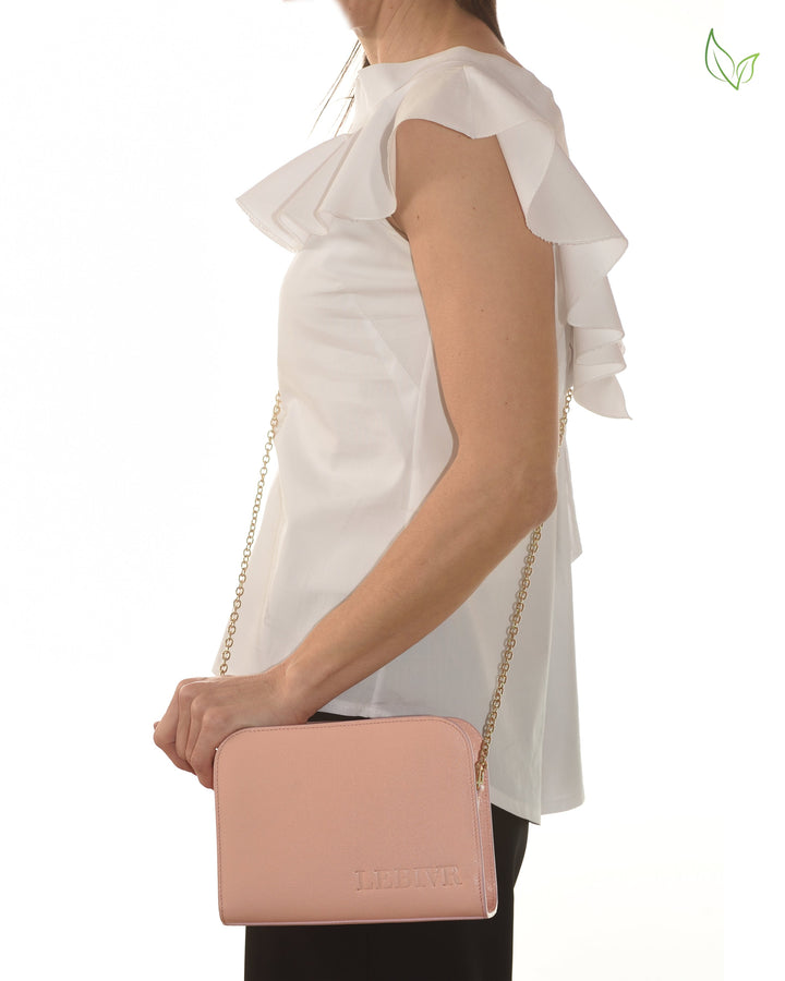 Woman wearing white ruffle sleeve top holding pink leather crossbody bag