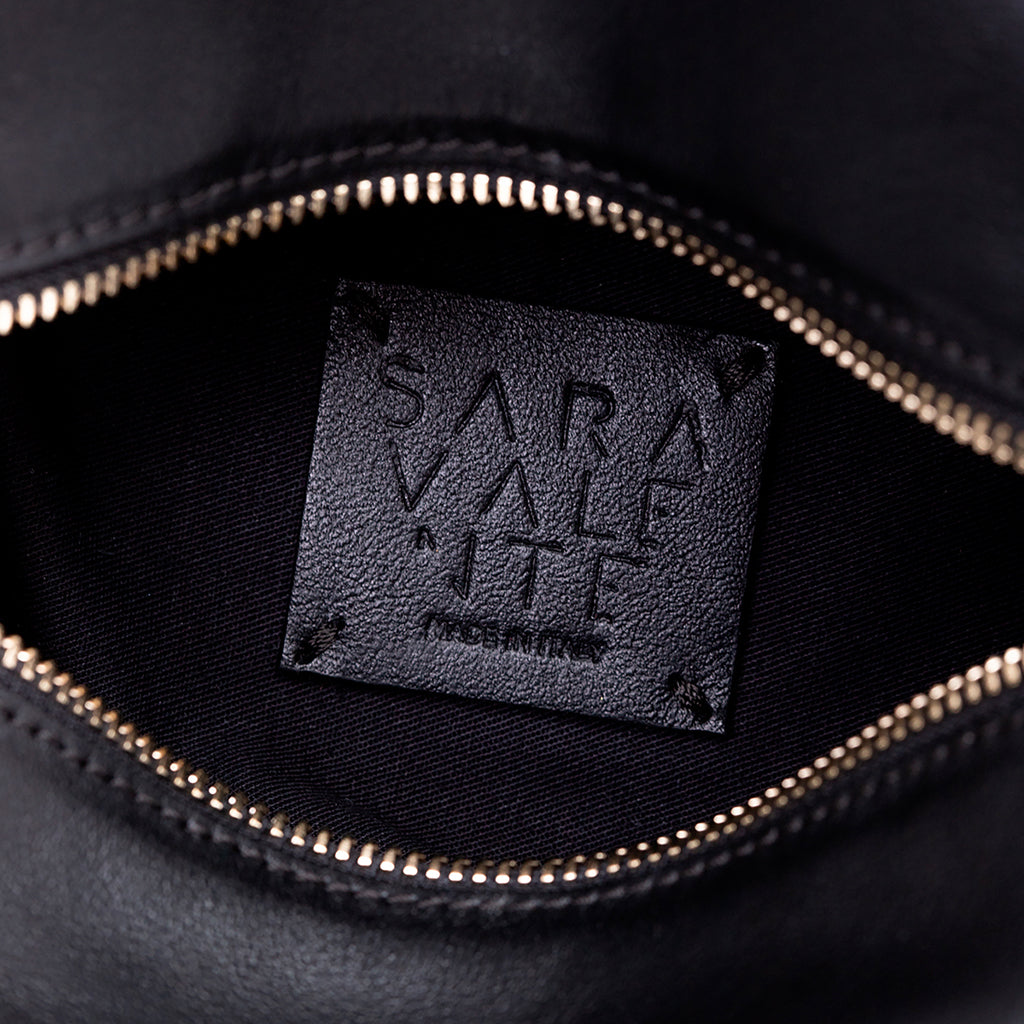 Close-up of a black leather bag with a Sara Valente logo inside