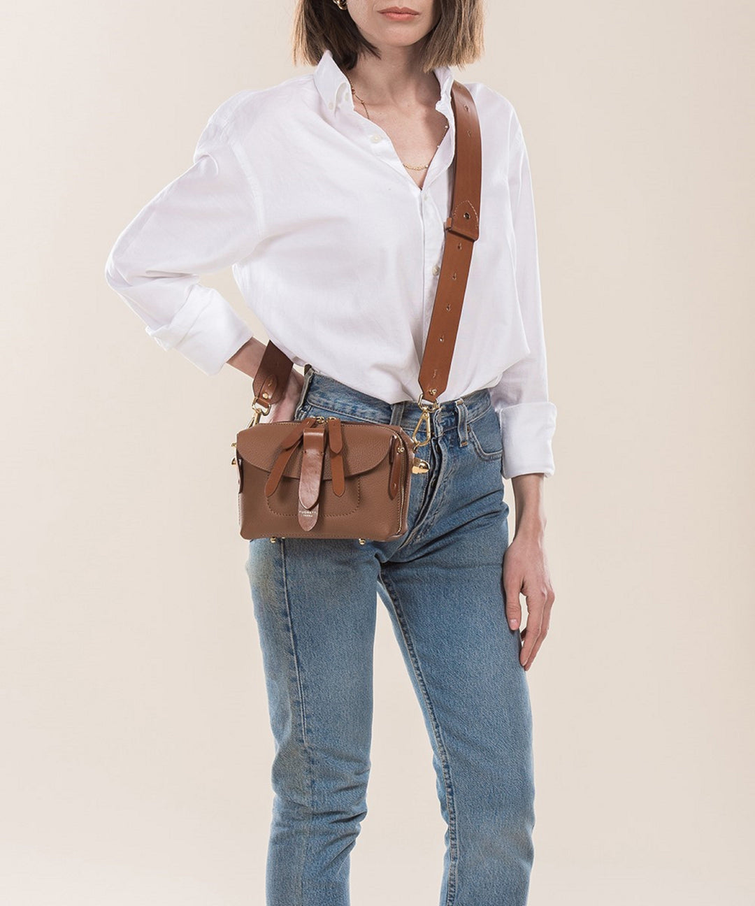 Woman wearing a white blouse and jeans with a brown leather crossbody bag