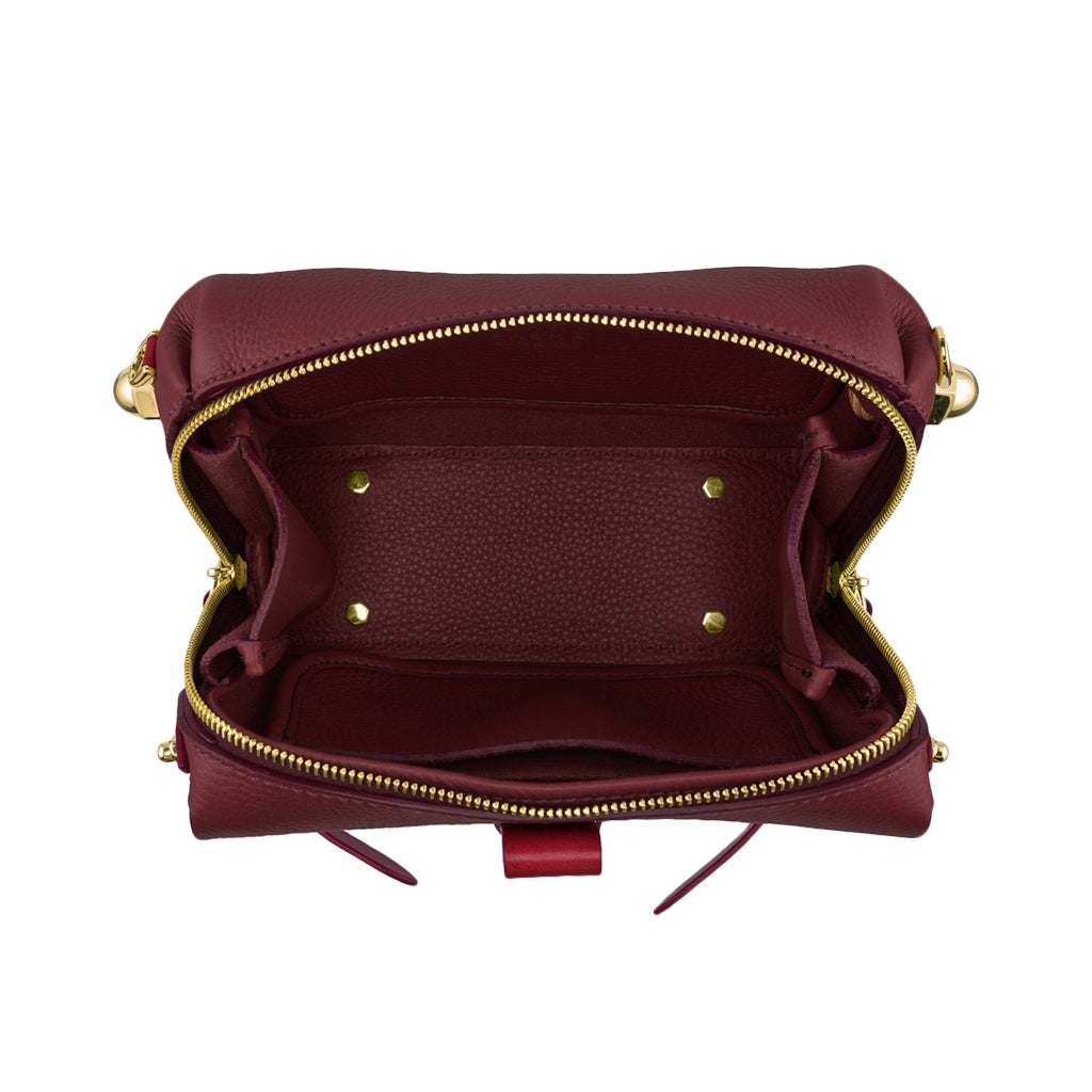 Interior view of an open maroon leather handbag with multiple compartments