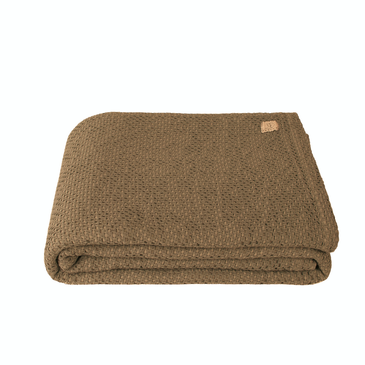 Folded brown waffle knit blanket on white background