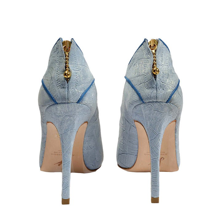 Light blue high-heeled shoes with intricate texture and gold zipper detail, viewed from the back