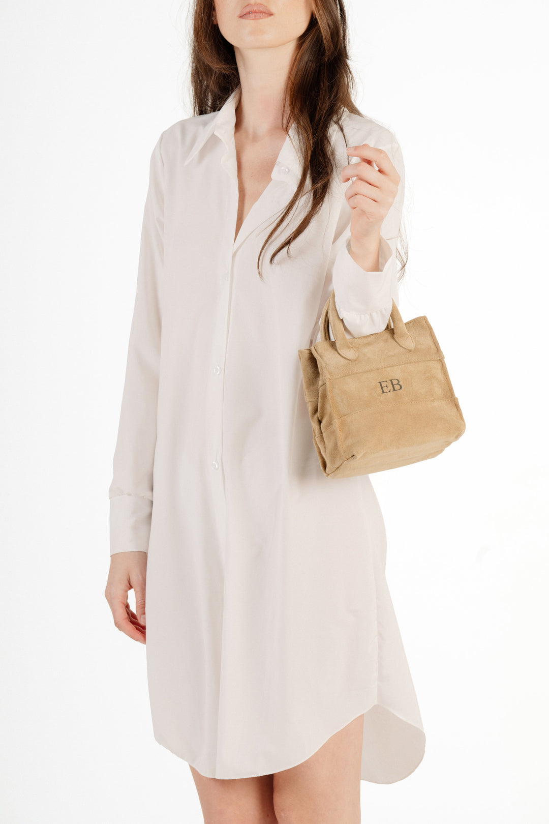 Woman in white shirt dress holding a small beige handbag