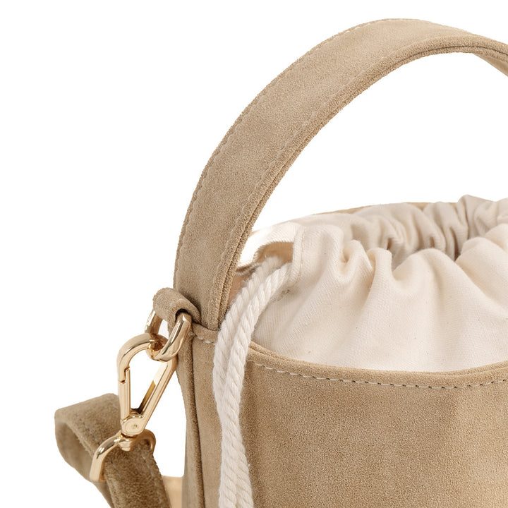 Beige suede bucket bag with drawstring closure and gold hardware clasp