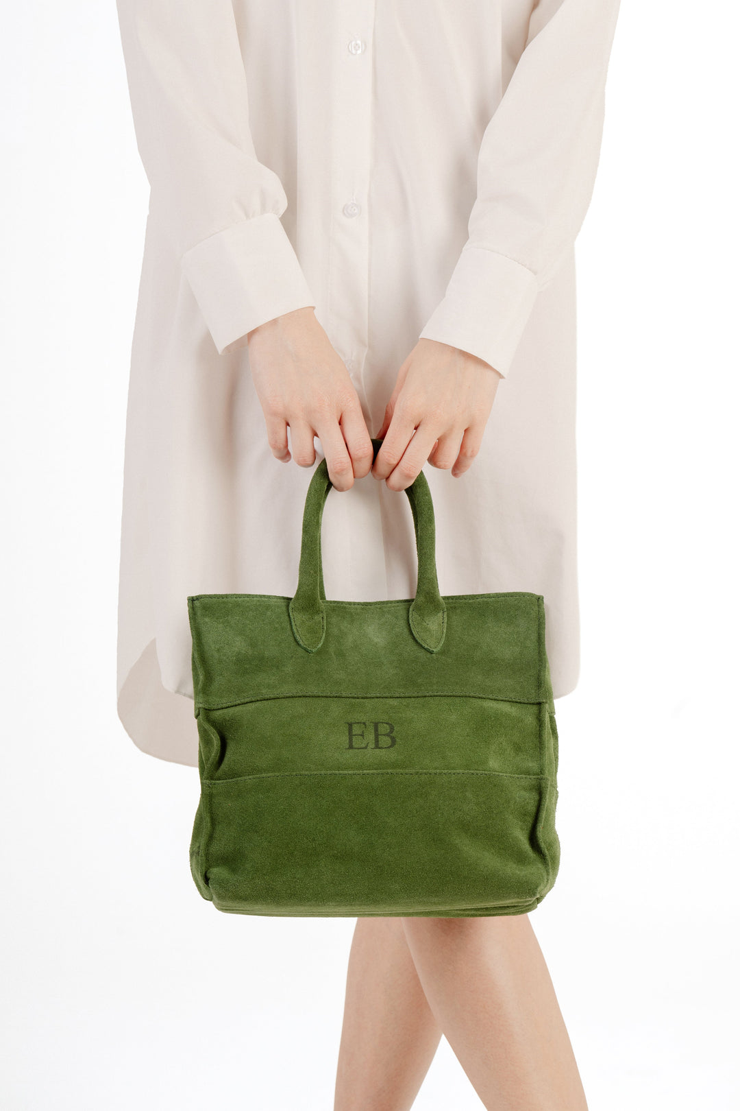 woman holding stylish green suede handbag with initials EB