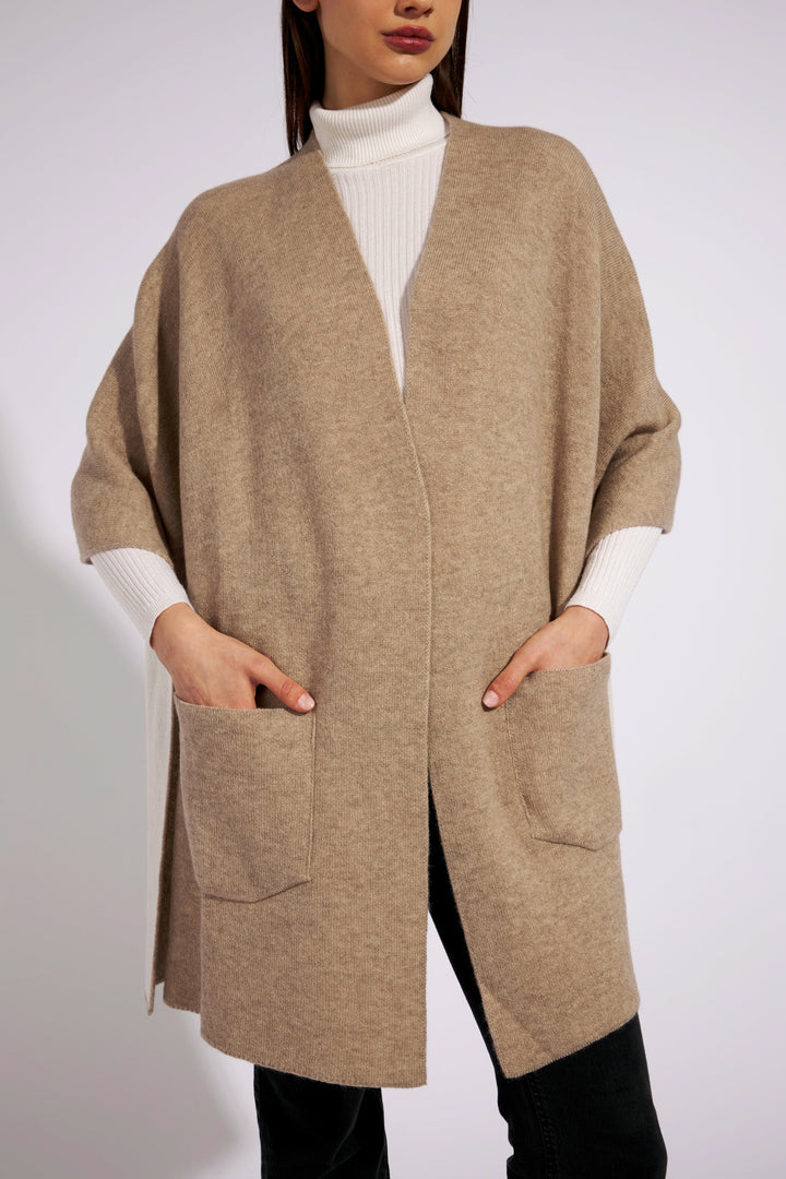 Woman wearing beige cardigan with front pockets and white turtleneck sweater