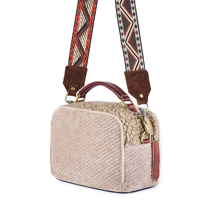 Beige textured shoulder bag with colorful, patterned strap and leather accents