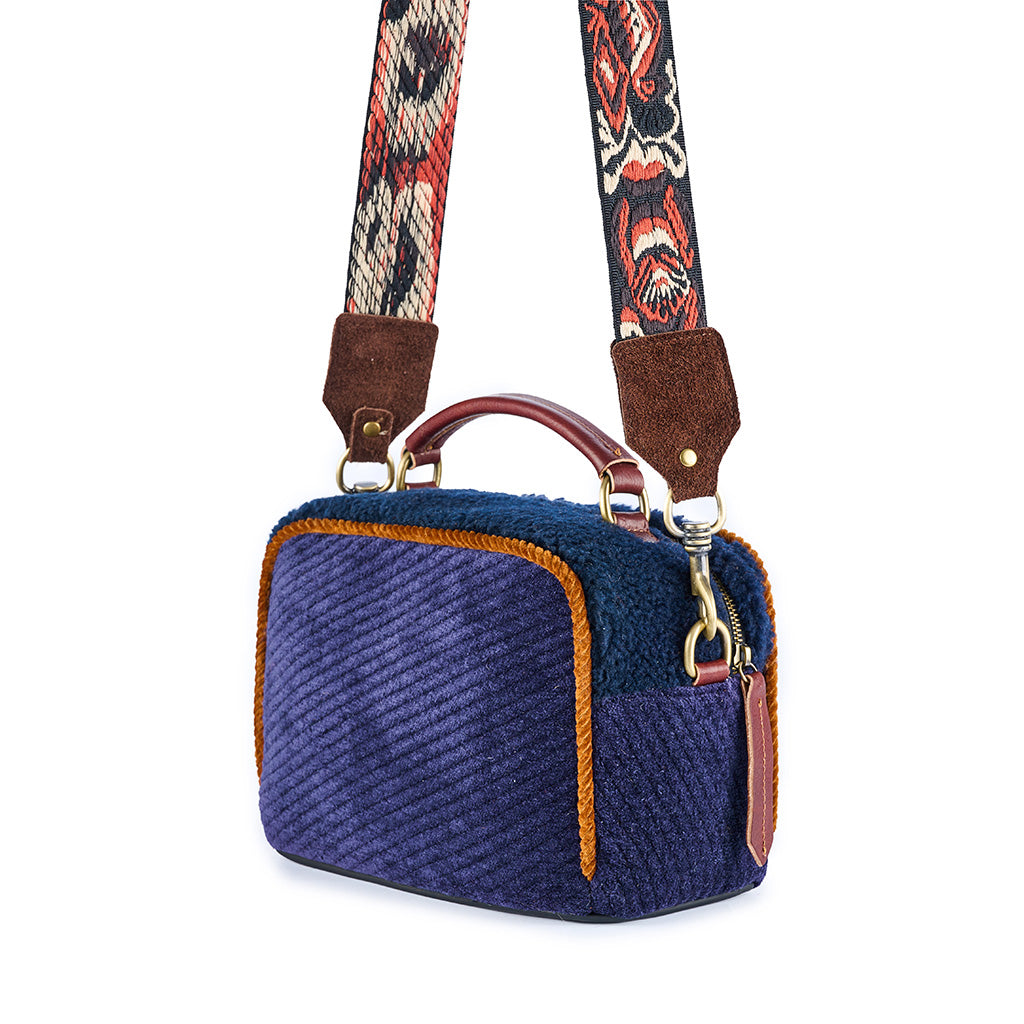 Purple corduroy handbag with colorful patterned strap and orange trim