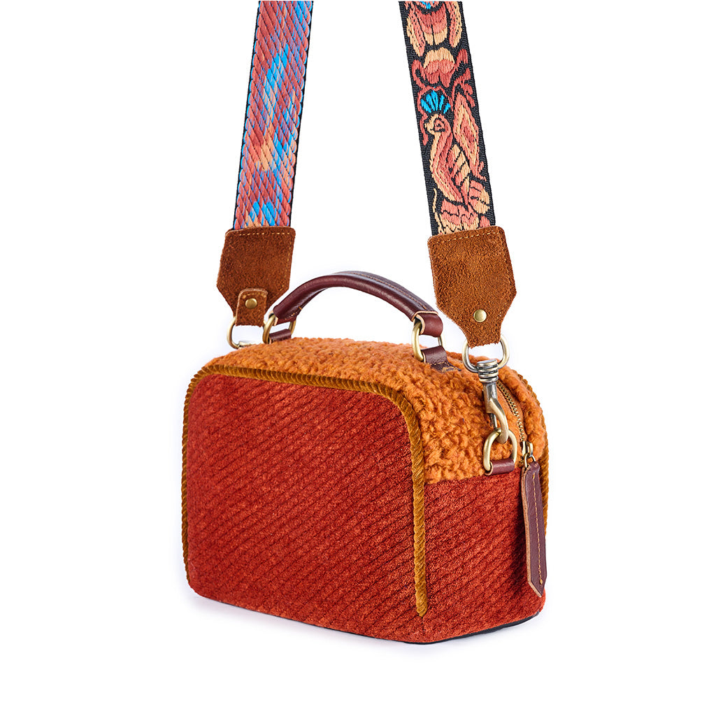 Rust-colored handbag with floral embroidered strap and textured fabric