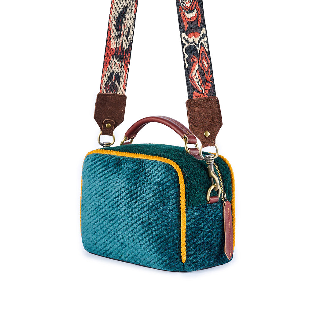 Teal textured handbag with colorful patterned strap and leather accents