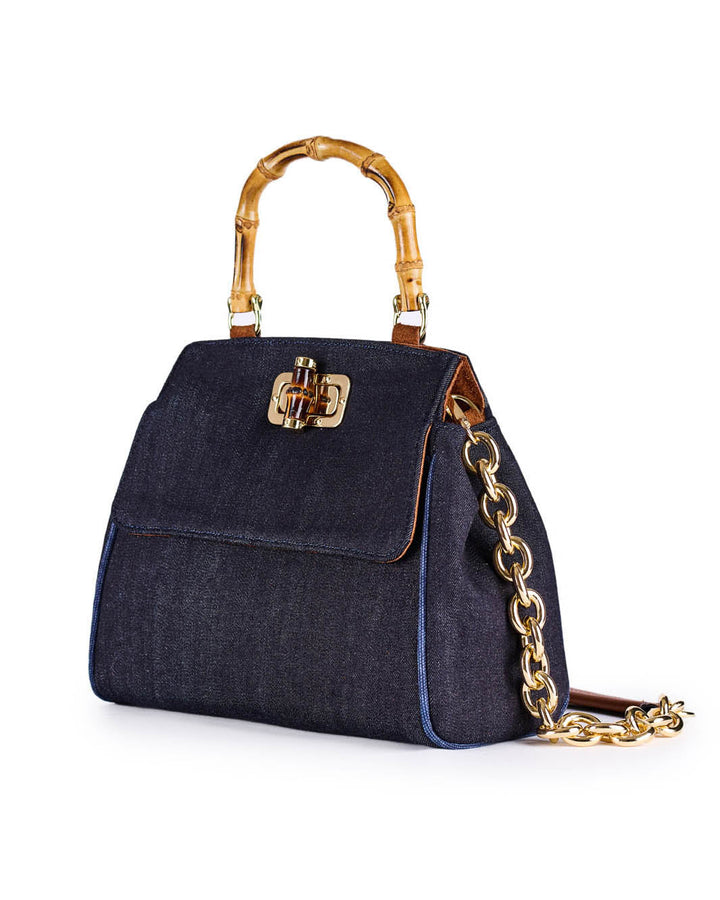 Denim handbag with bamboo handle and gold chain strap on white background