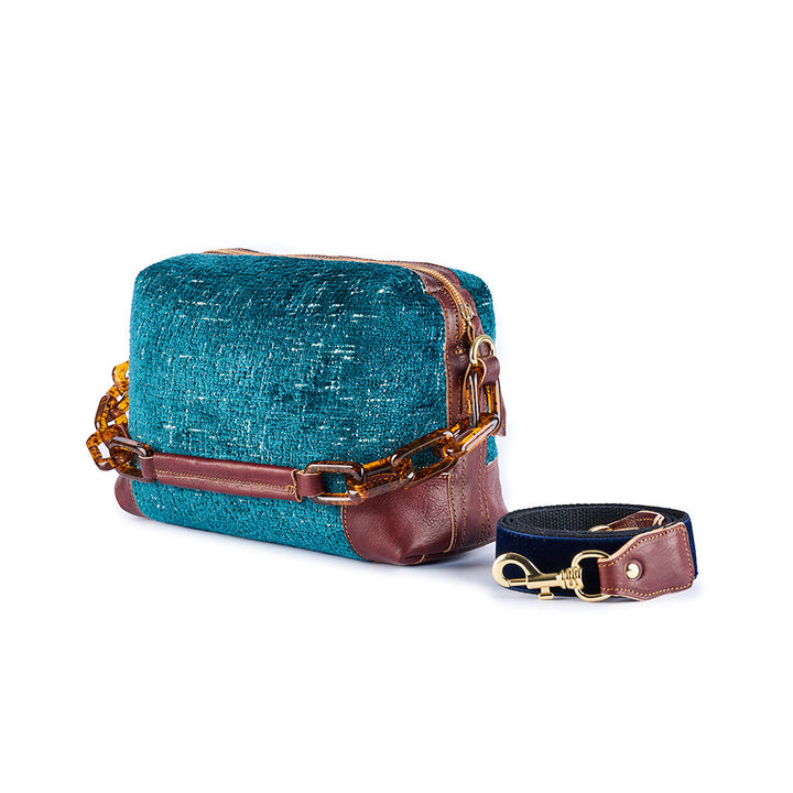Teal textured handbag with brown leather accents and detachable strap featuring gold hardware