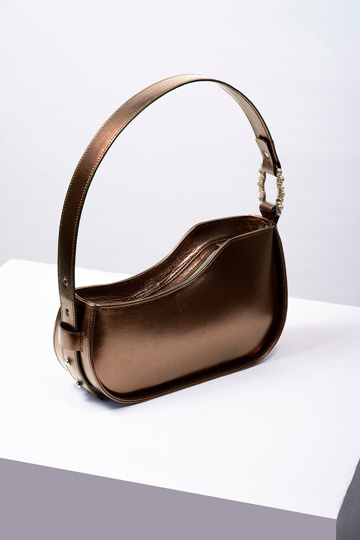 Bronze metallic leather handbag with single strap on white surface