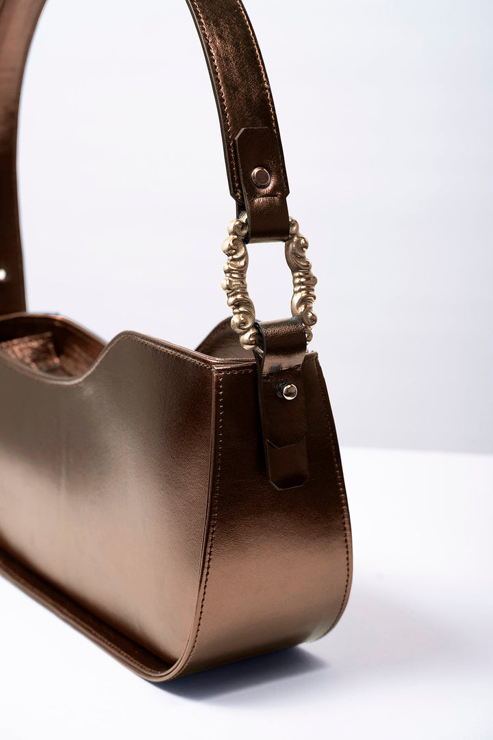 Close-up of a stylish brown leather handbag with decorative brass hardware