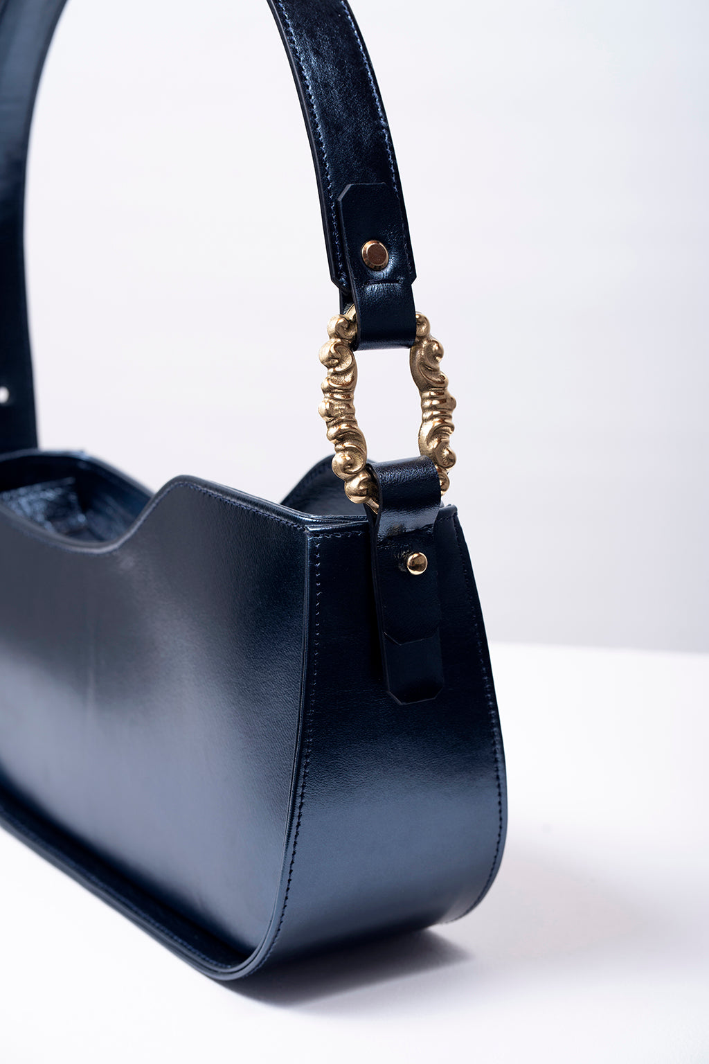 Close-up of a stylish dark blue leather handbag with brass accents