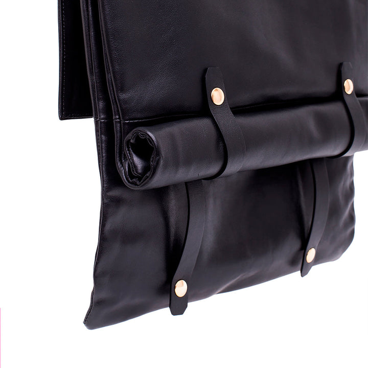 Black leather backpack with roll-top closure and brass button accents