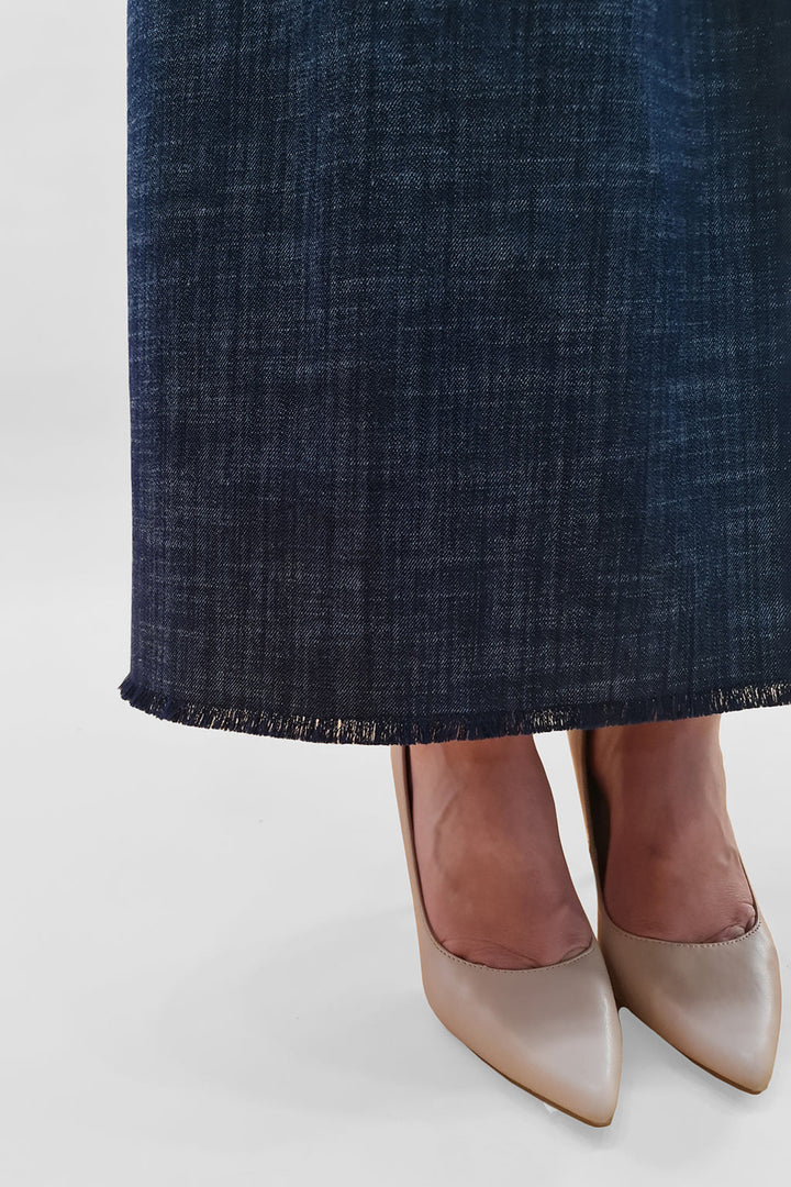 Close-up of a person wearing beige high-heeled shoes and a dark blue denim skirt