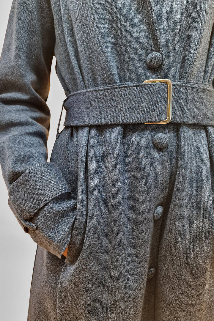A close-up of a stylish grey wool coat with buttons and a belt detailing