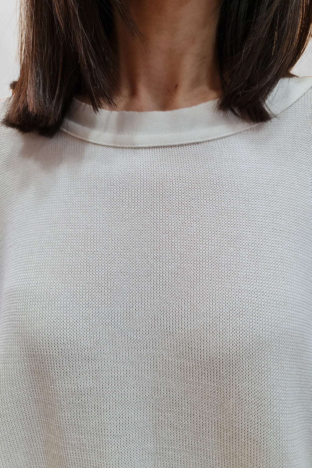 Close-up of a person wearing a white textured long-sleeve shirt
