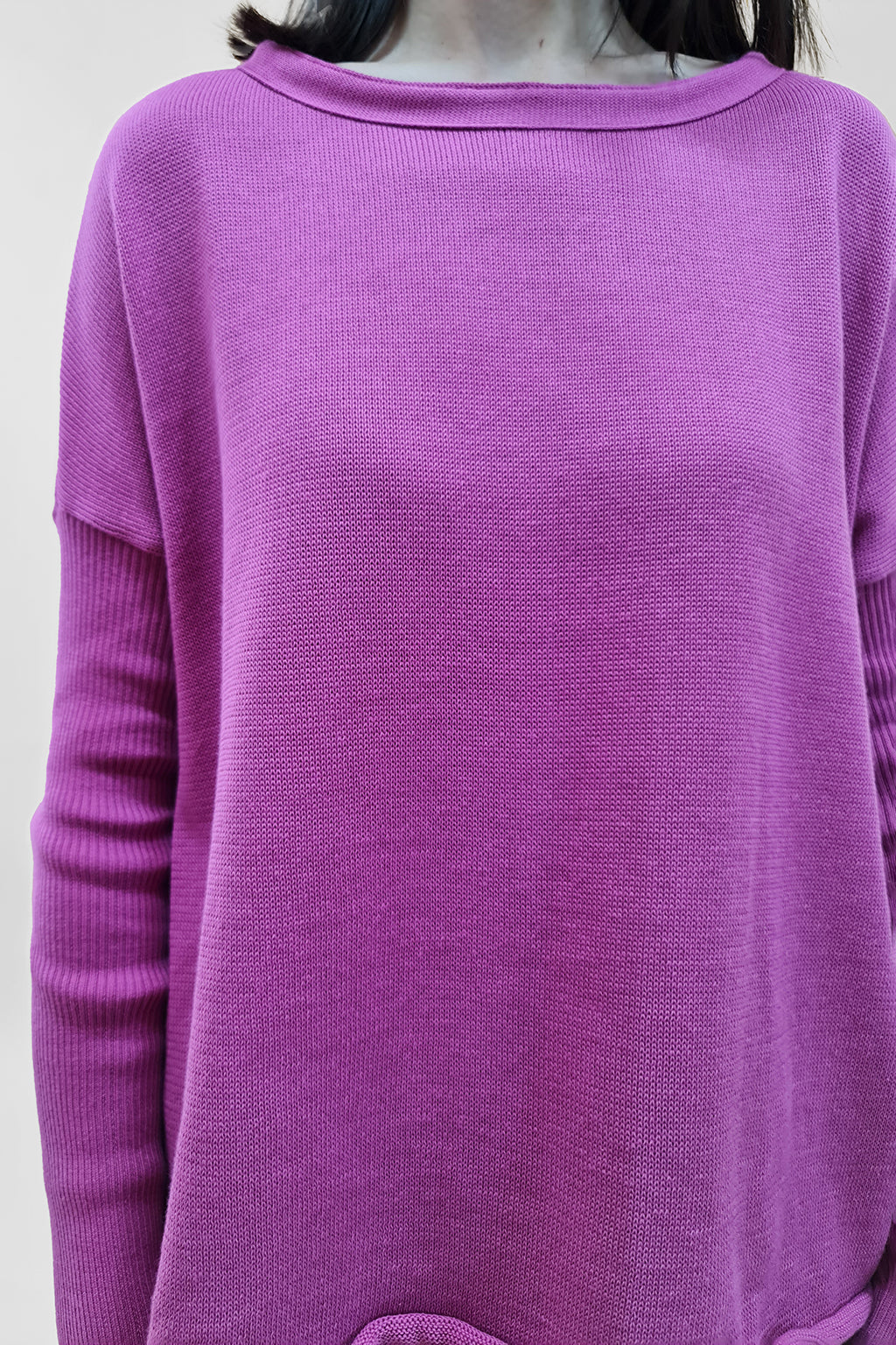 Close-up of a woman wearing a vibrant pink sweater with a textured knit pattern