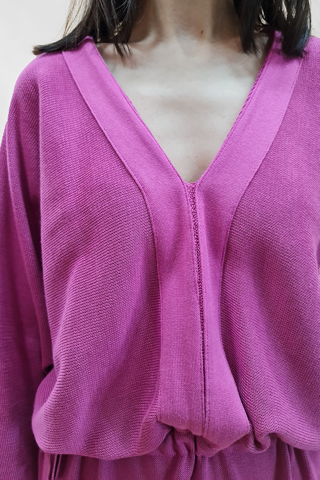 Close-up of woman wearing a vibrant pink V-neck sweater