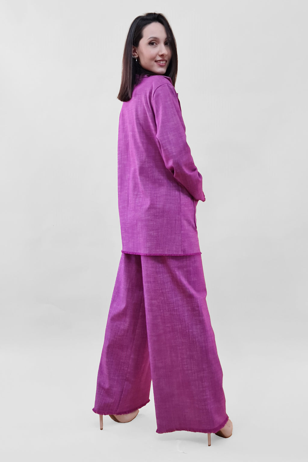 Woman in a fuchsia pantsuit posing against a white background