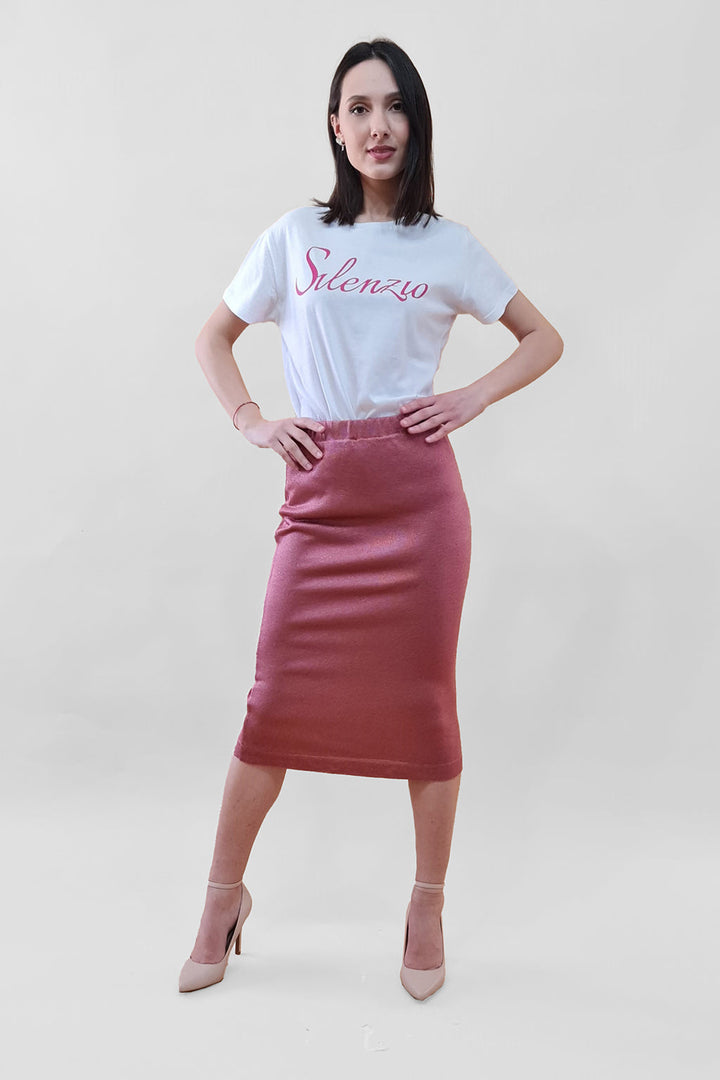 Woman in a white Silenzio t-shirt and pink pencil skirt posing against a plain background