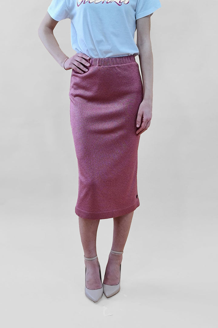 Woman wearing a pink midi skirt and white top with beige high heels