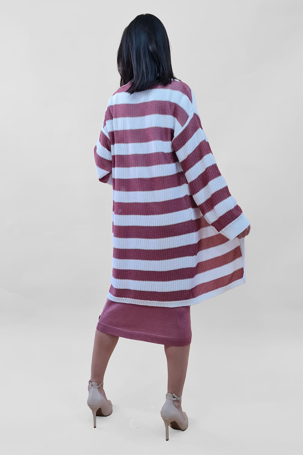 Woman wearing a striped oversized cardigan and high heels, viewed from the back