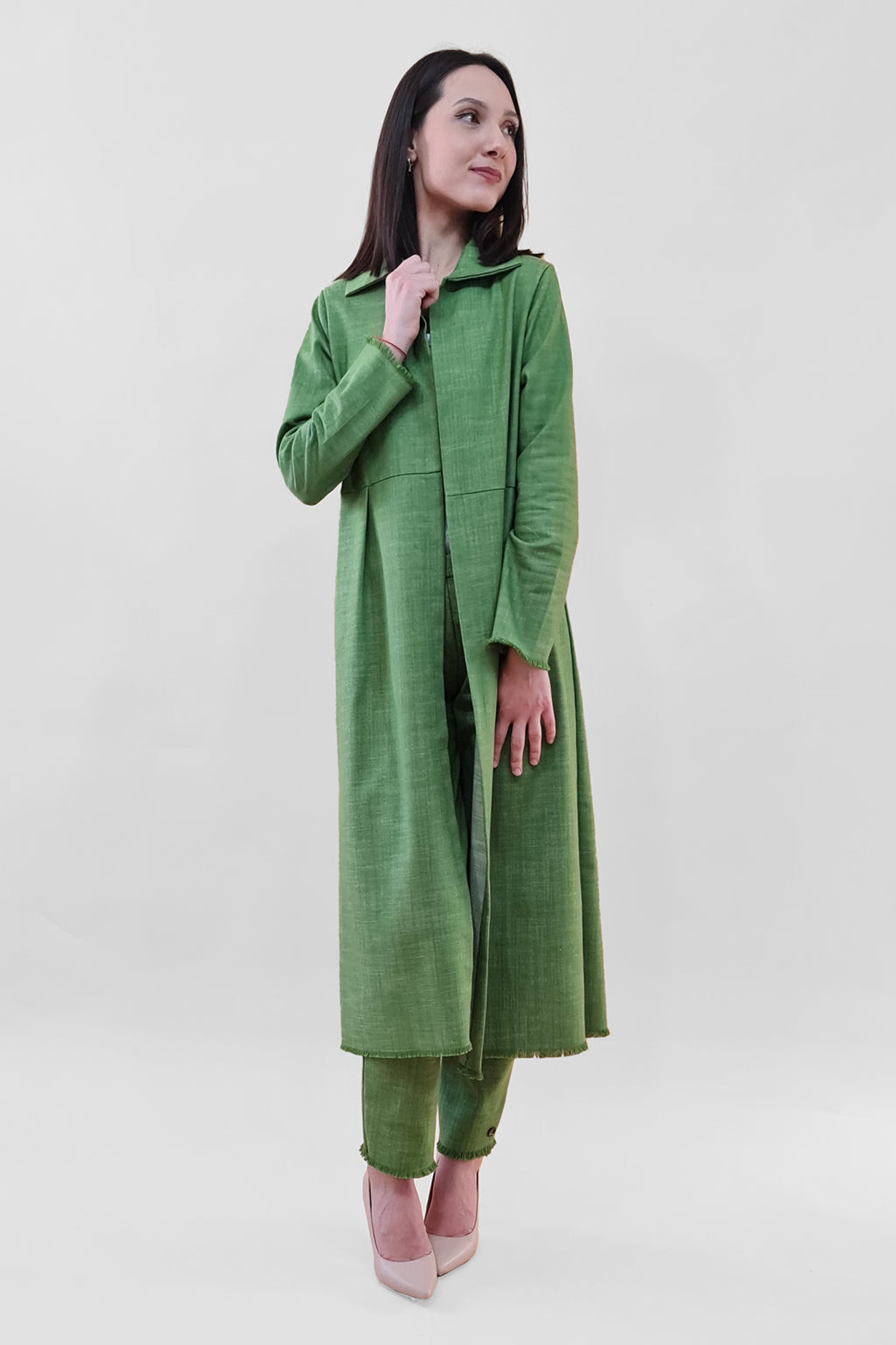 Woman in green traditional outfit poses confidently against white background