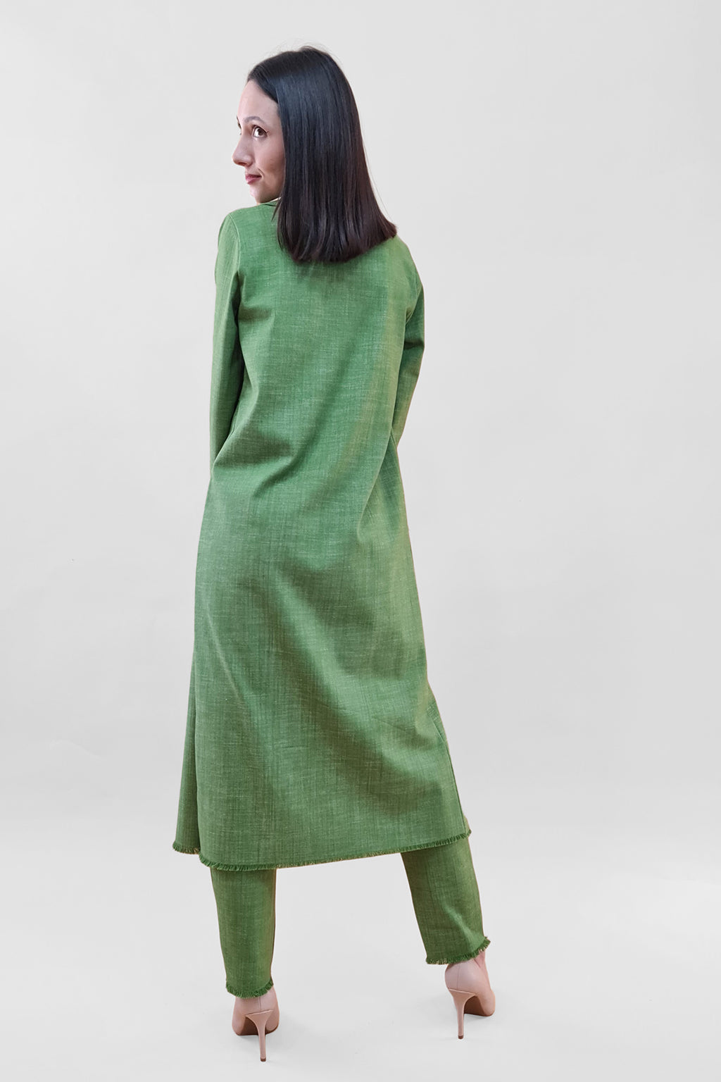 Woman in a green traditional outfit facing away on a white background