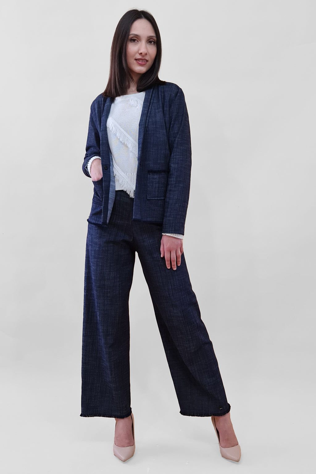 Woman wearing a navy blue pantsuit with a white blouse and beige heels