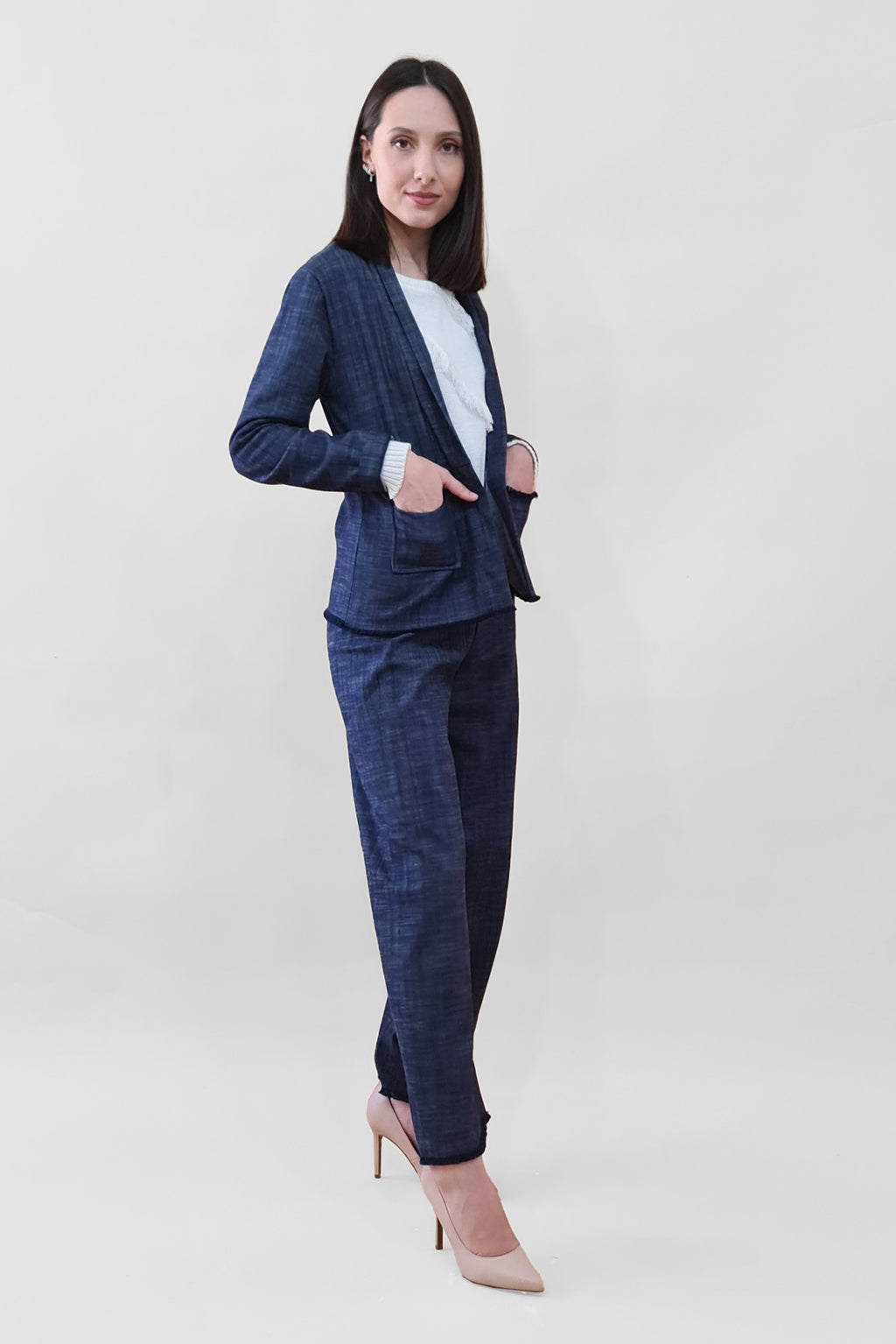 Woman wearing a navy blue plaid suit with white top and nude heels against a plain background