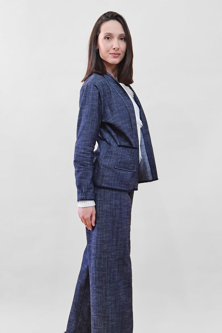 Woman wearing a blue plaid business suit standing sideways against a plain background