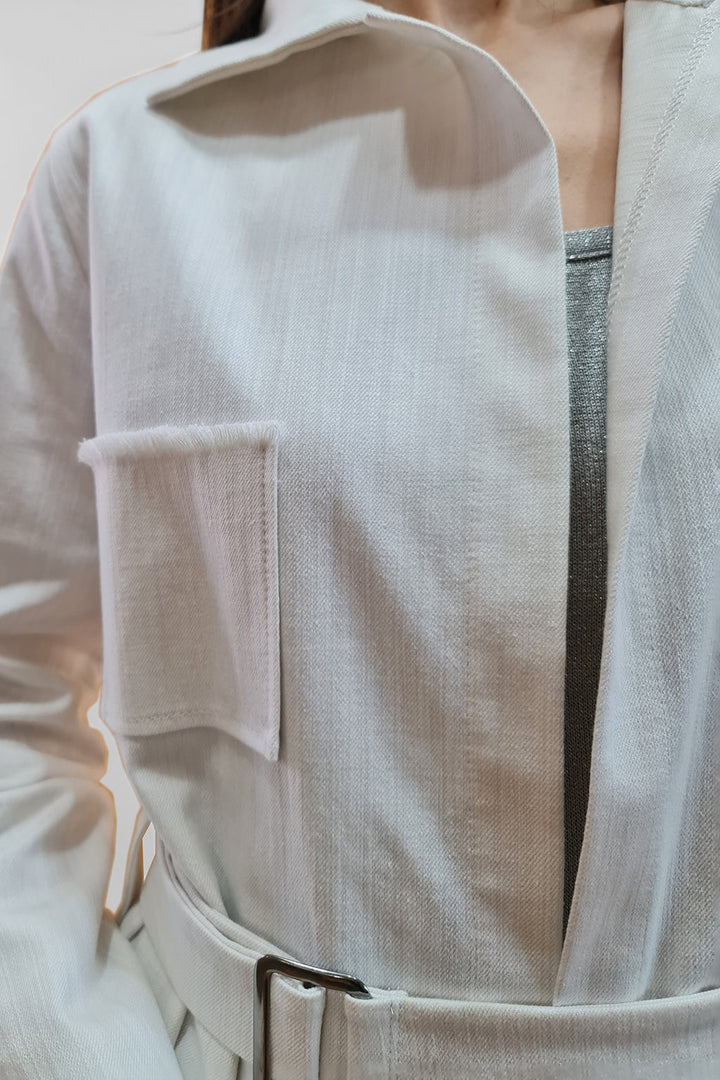 Close-up of a person wearing a stylish white jacket with a front pocket and belt