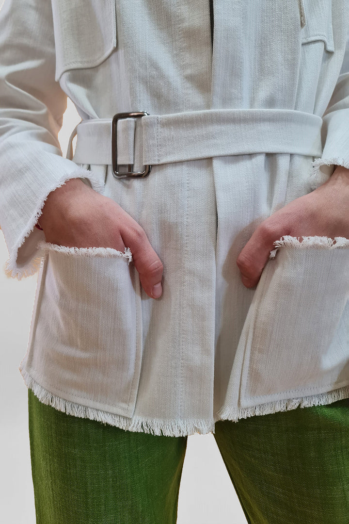 Person wearing a white belted jacket with pockets and green pants