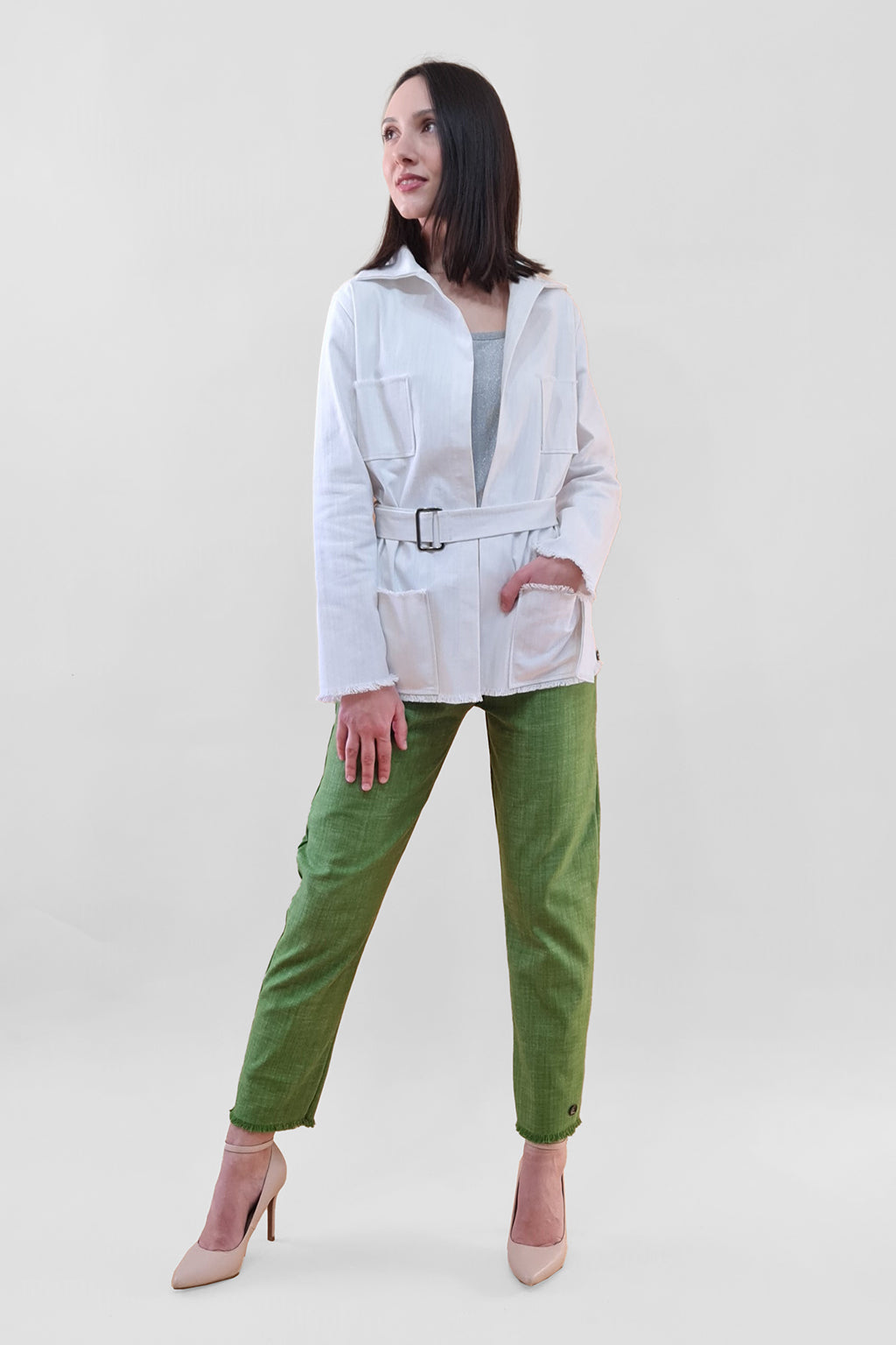 Woman wearing a white belted jacket and green pants with beige heels